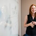 Emprego em Holding de Perfumaria e Cosméticos: 83 Vagas Abertas woman in blue tank top standing beside white wall