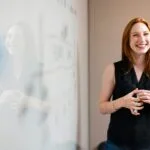 Emprego em Holding de Perfumaria e Cosméticos: 83 Vagas Abertas woman in blue tank top standing beside white wall