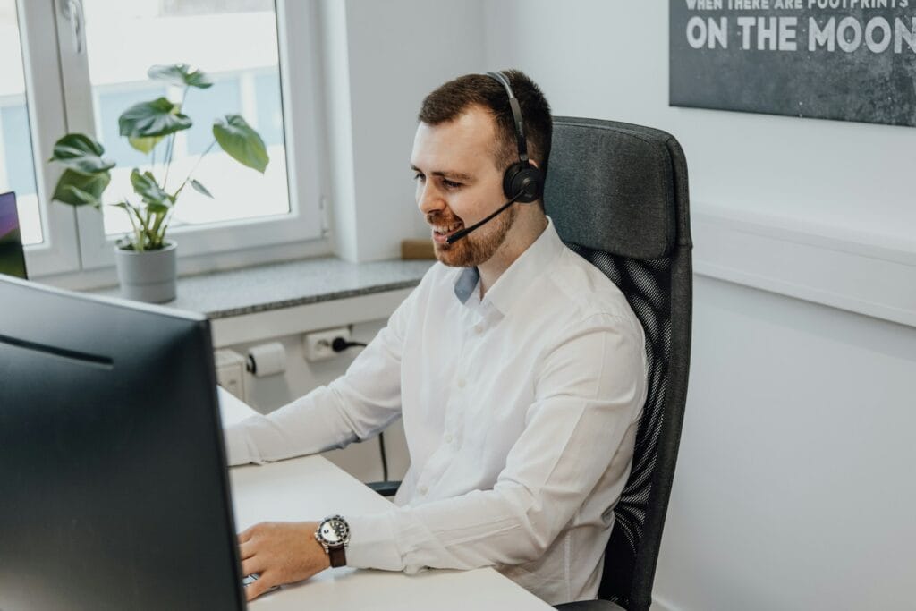 Vagas Remotas em Atendimento e Cobrança a man wearing a headset sitting in front of a computer