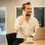 Vagas de Emprego na AVIVA: 17 Oportunidades Abertas man using smartphone on chair