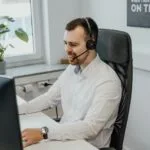 Vagas Remotas Abertas no SINIBREF a man wearing a headset sitting in front of a computer